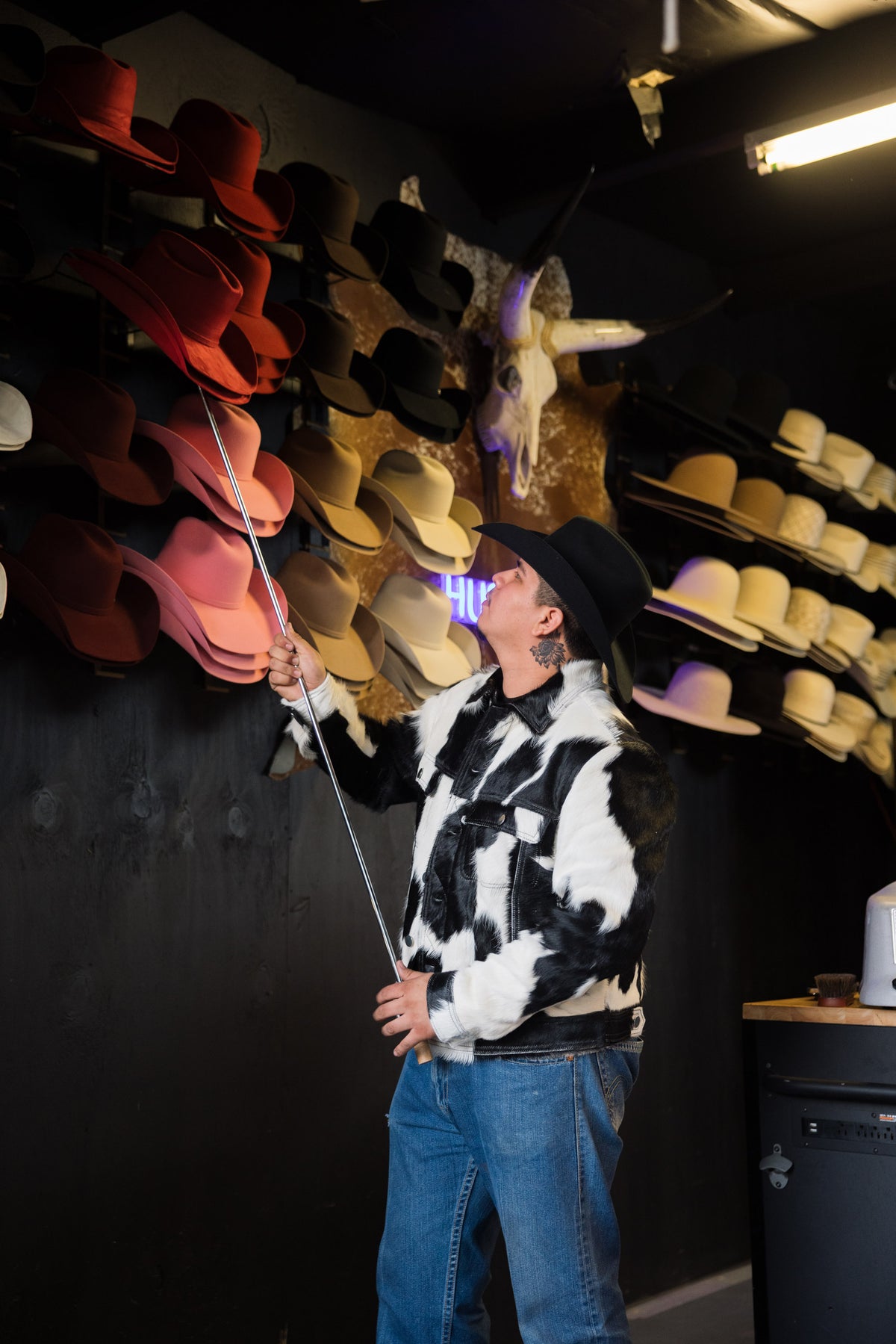 Pulling a felt hat down from the hat wall at the Third Coast Hat Bar