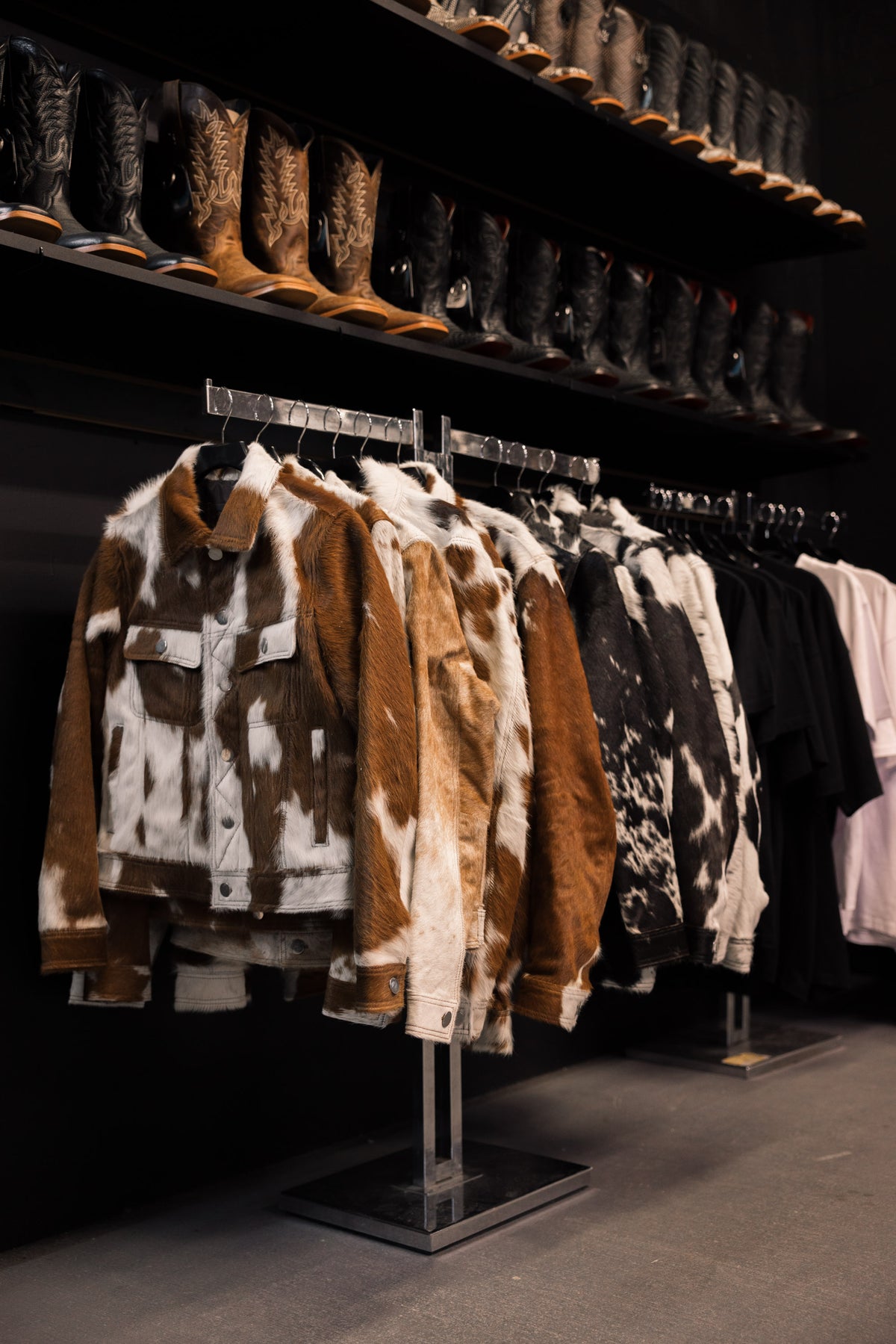 Cowhide jackets on the rack under a shelf of boots at the Third Coast booth