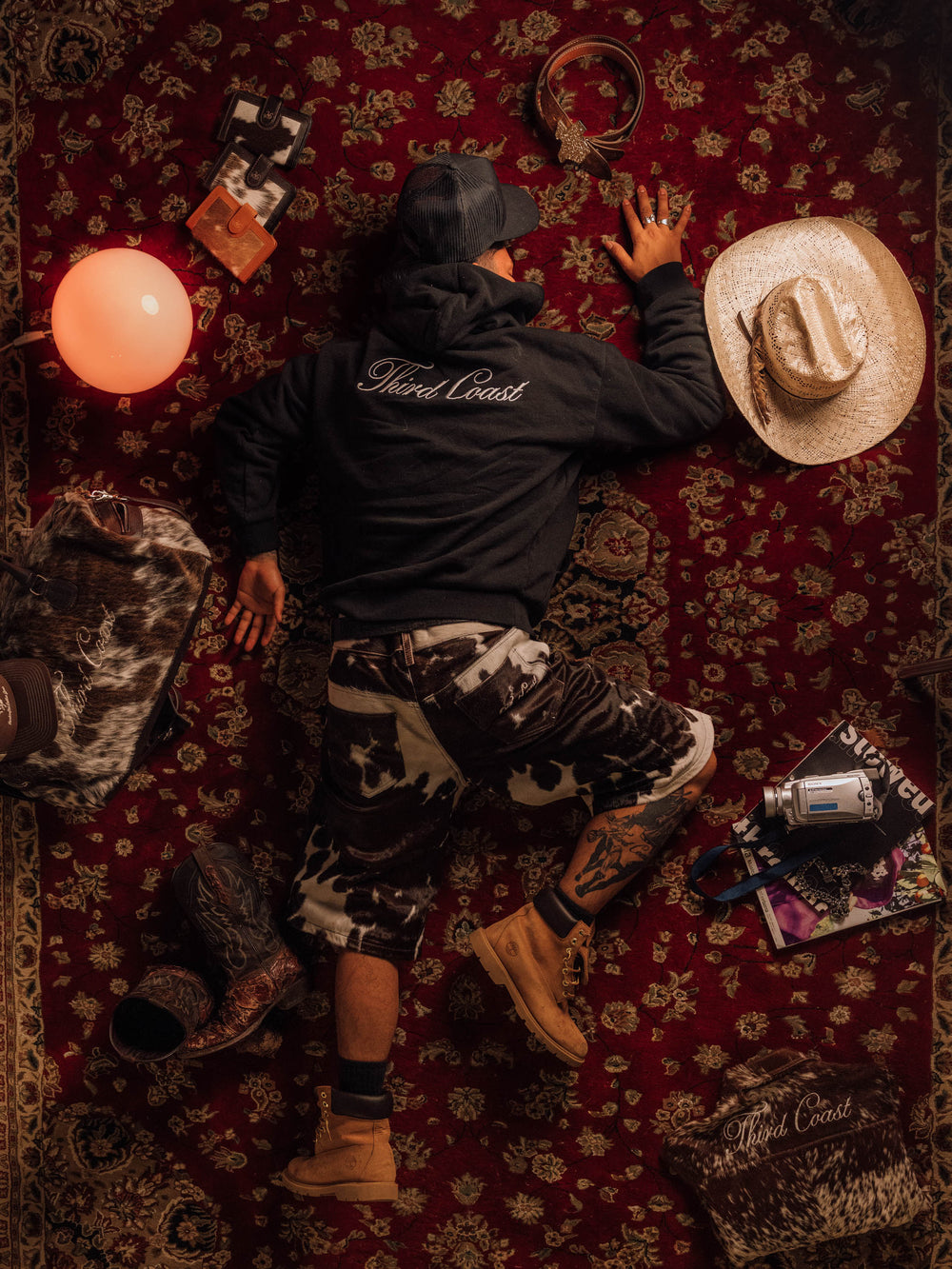 Black TC Hoodie with Third Coast script across the back, worn with cow-print pants and work boots