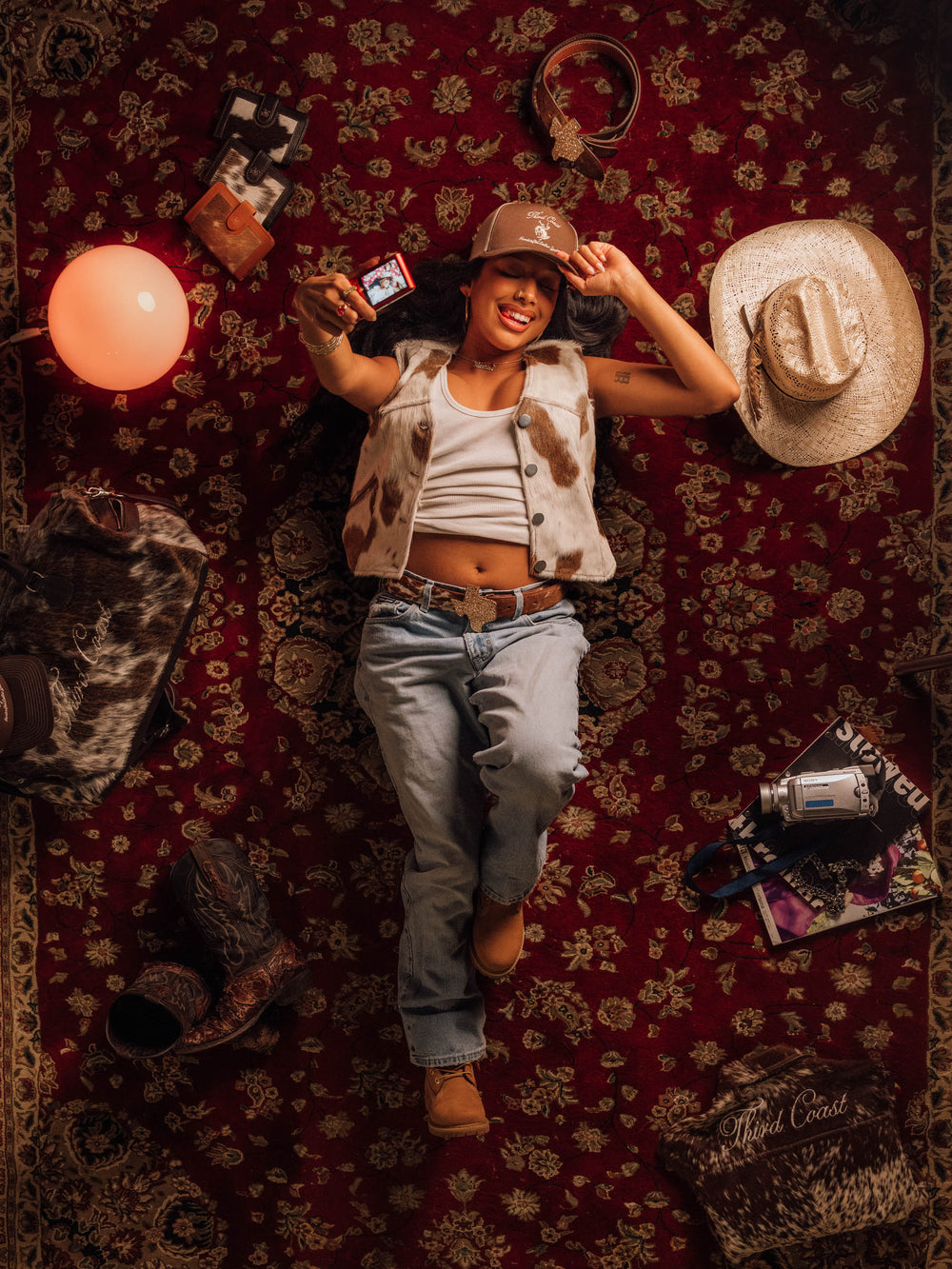 Heritage No. 1 Ladies Vest in Red Angus with light-wash jeans and a ball cap, laid out on a red rug