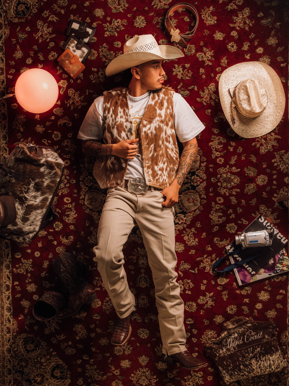 Heritage No. 1 Vest in Red Angus with a straw cowboy hat, white tee and khakis, on a red rug